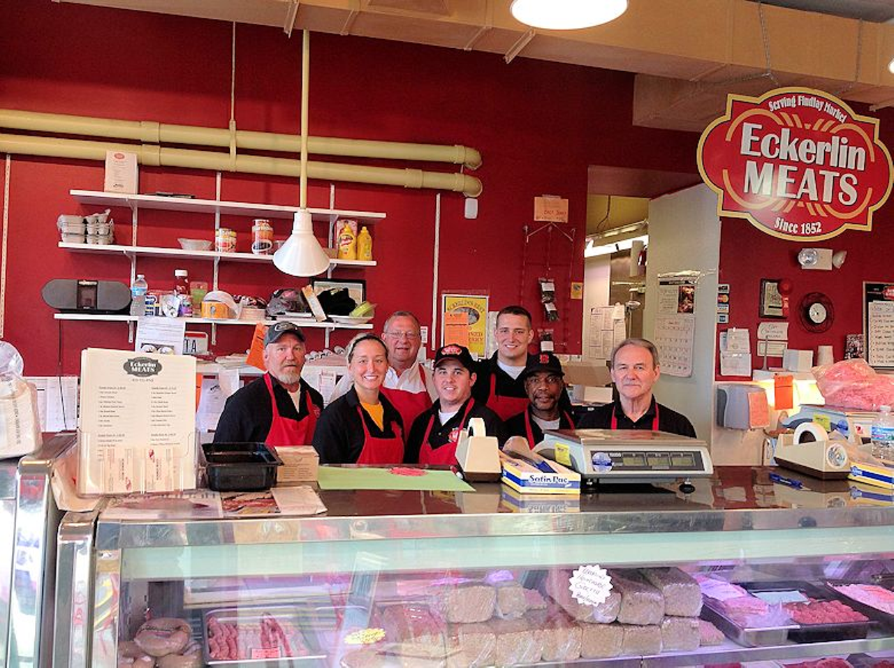 Eckerlin Meats
Egg and Cheese On A Roll, $4
Eckerlin’s egg and cheese is the only sandwich I had tried prior to this tour, as I often take out of town guests to Eckerlin Meats so they can try goetta. In addition to a full deli, Eckerlin offers their breakfast sandwiches until 2 p.m. on Sundays and 3 p.m. Tuesday-Saturday, which is a big plus. You order at the counter and then pick up your food from a window in the hallway, with seating available in the back in addition to Findlay Market’s outdoor tables. The sandwich itself is nothing special or fancy – almost giving Wonder Bread grilled cheese cut on the diagonal vibes. But at $4 a pop, Eckerlin delivers on delicious simplicity.
Served on a slightly sweet North College Hill Bakery white roll with a slice of American cheese, Eckerlin’s egg sandwich comes with zero fixings. I prefer mine with ketchup and hot sauce for a little acid, but other than that, I have no complaints. The egg is cooked over medium, (a rarity for non-homemade sandwiches), allowing for its namesake ingredient to shine through with jammy yolk goodness rather than serving as a mere backdrop to toppings. On the smaller side, you could easily order this sandwich and still save some room for other tasty treats at Findlay.
Fast, cheap, simple – Eckerlin’s egg and cheese hits every time. For meat eaters, you can order it with goetta, bacon, sausage, beef bacon or smoked mett for an additional $1.50-$2.50. I suggest ordering the goetta well done so you have a bit more textural diversity from the soft bun. Also, pro-tip, grab yourself a bag of NCH bakery’s cinnamon swirl bread while you’re there for toast or French toast when you get home.