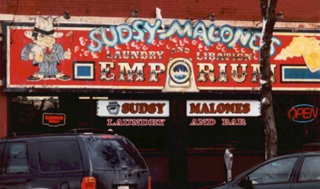 Sudsy Malone’s
Sudsy Malone’s Rock & Roll Laundry & Bar was both a laundromat and a music bar on Short Vine in Corryville. The business opened in 1986 and hosted smaller rock and indie acts (many of which became famous later on, like Red Hot Chili Peppers and Smashing Pumpkins). The bar/laundromat closed in 2008, and the building was demolished in 2020.

“I was just a couple years too young to experience Sudsy Malone's - but it was half laundromat half venue that had death metal karaoke and shows. Just a legend by the time I was a UC student.” -u/acanofspam

“It was my favorite place to both see and play punk rock. So many great bands and people.” -u/Awkward-Tangelo5181
“I was a doorman there for the rear entrance from the back parking lot in the summer of 91'. We had a cover charge, or you could get in free if you had a bag of laundry to wash. I remember people just sitting on the washing machines watching the shows.” -u/rawfish71