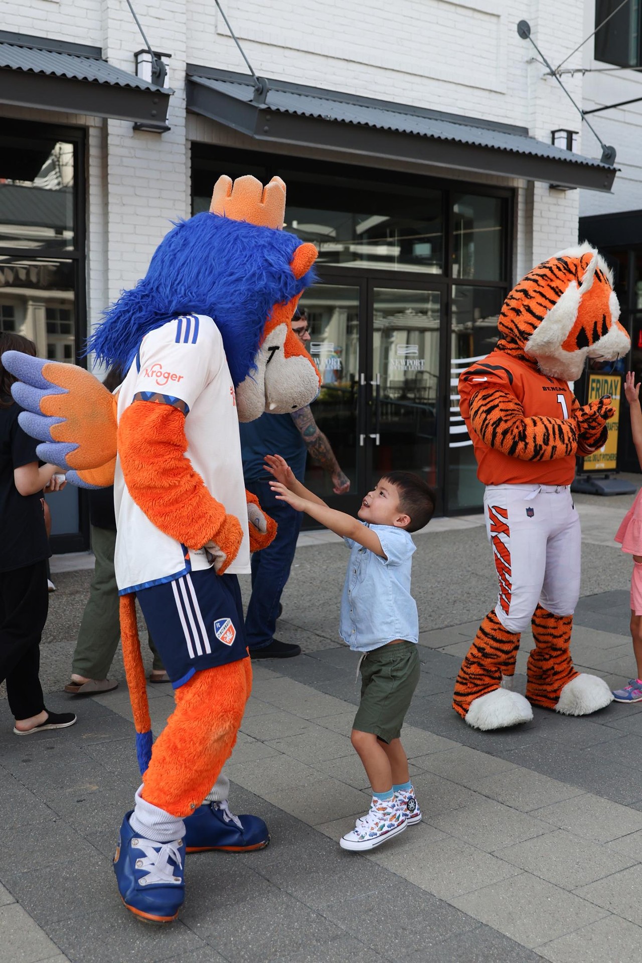 A young fan gives Gary the Lion a hug at the Olympic Opening Ceremony celebration at Newport on the Levee on Friday, July 26, 2024.