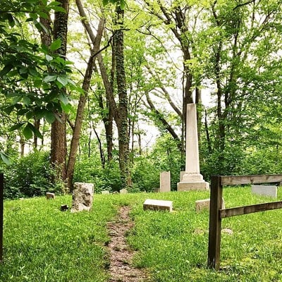 Darby-Lee CemeteryCan be accessed from the Bender Mountain Trail, 6320-6468 Bender Road, Delhi TownshipWest Siders, you may have heard of Fiddlers Green Road, but have you heard the legend of Fiddler’s Green? (Which actually has nothing to do with that particular road.) It goes back to the Darby-Lee family of Delhi Township, members of which are buried in a small graveyard at the top of Bender Mountain – the only known, remaining family cemetery in Delhi. Patriarch of the family Henry Darby was rumored to have been part of the Underground Railroad. The legend of Fiddler’s Green goes that he would sit up on the ridge of his property overlooking the Ohio River into Kentucky. When it was safe for those fleeing enslavement to cross the river and come up the ridge to his home, Darby would light a lantern with a green flame and play his fiddle. On some nights now, you can supposedly see an otherworldly green glow from the cemetery and hear the strains from a fiddle being played nearby.